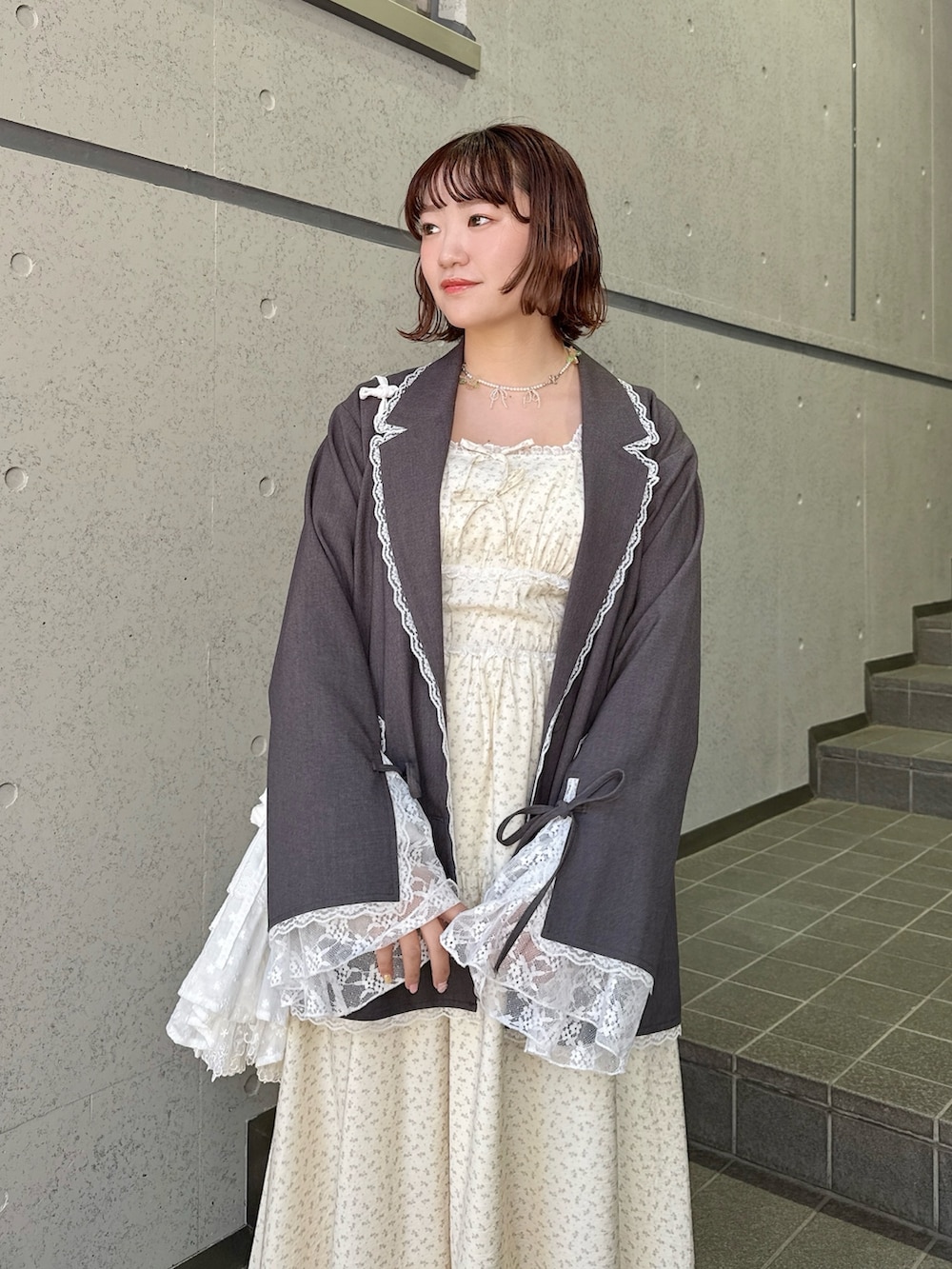 グレー系のテーラードジャケット、ベージュ系のワンピース、ホワイト系のショルダーバッグを着用したレディースの冬コーディネートの4枚目の写真