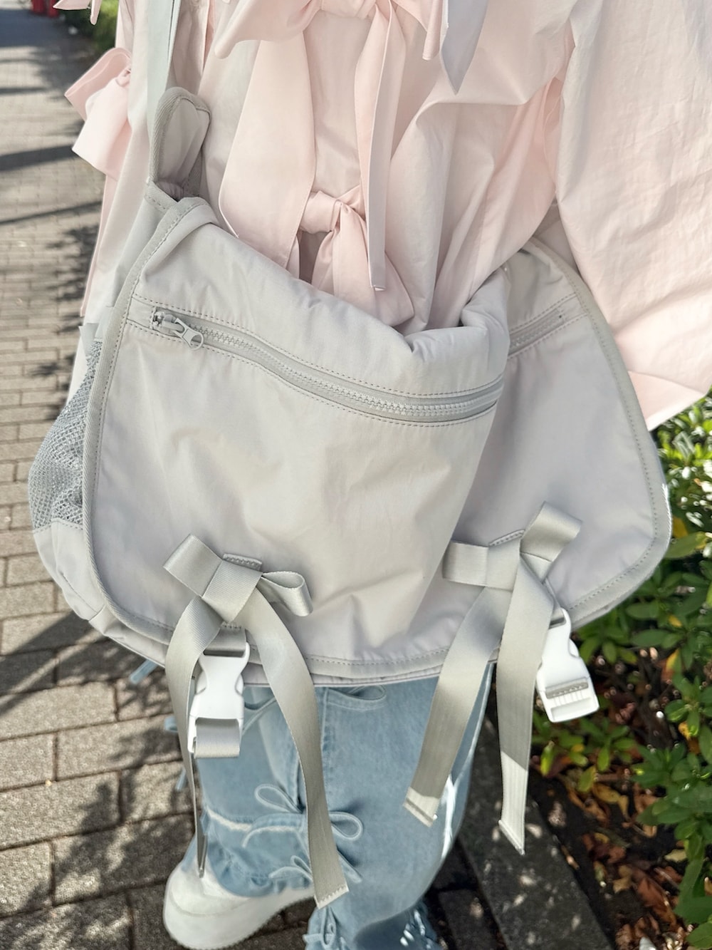 ピンク系のシャツ/ブラウス、グレー系のメッセンジャーバッグ、ブルー系のデニムパンツを着用したレディースの冬コーディネートの5枚目の写真