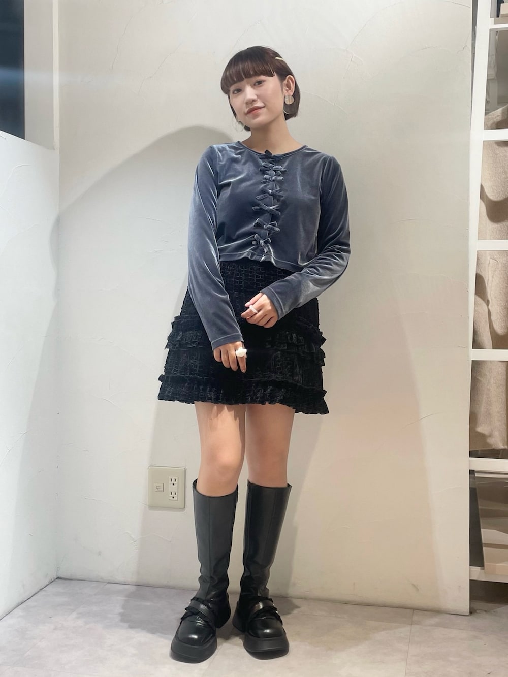 ブラック系のスカート、ブルー系のカーディガン/ボレロ、ブラック系のブーツを着用したレディースの冬コーディネートの2枚目の写真