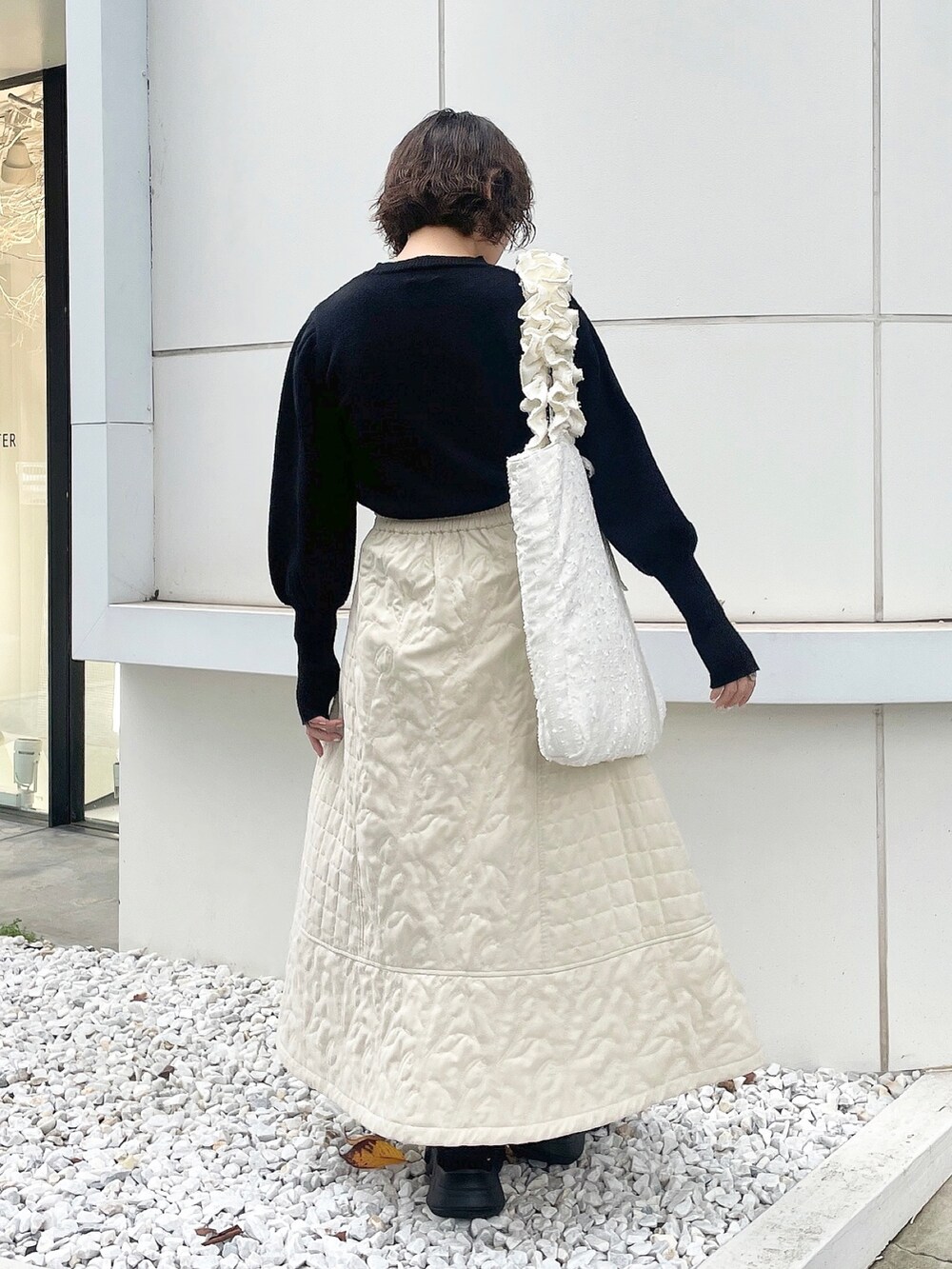 ブラック系のニット/セーター、ホワイト系のハンドバッグ、ホワイト系のスカートを着用したレディースの秋コーディネートの4枚目の写真