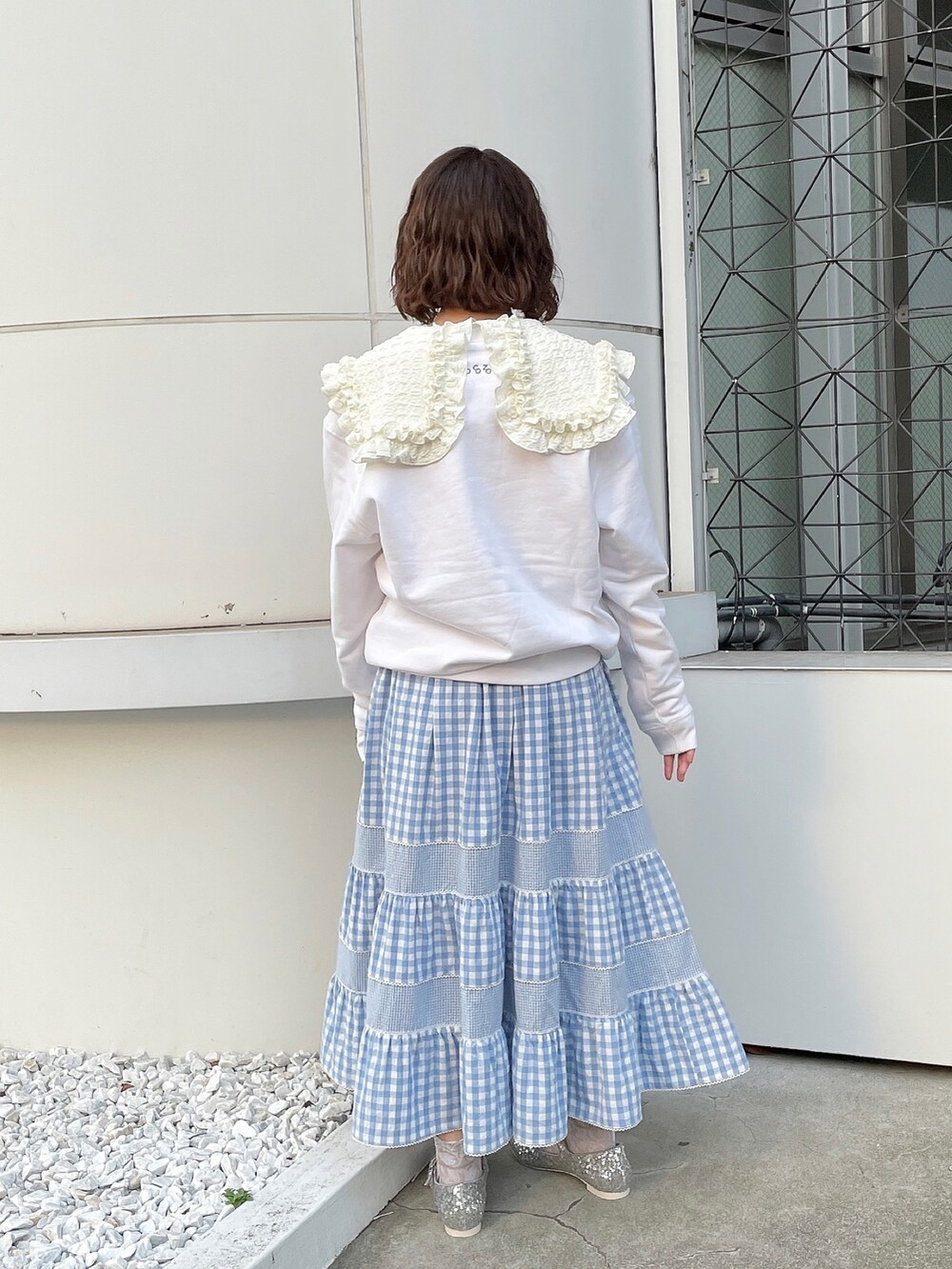 ホワイト系のスウェット、ホワイト系のTシャツ/カットソー、ブルー系のスカートを着用したレディースの冬コーディネートの3枚目の写真