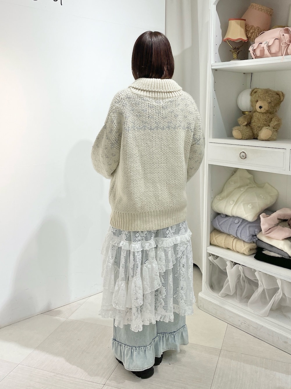 ホワイト系のニット/セーター、ブルー系のデニムパンツ、ホワイト系のスカートを着用したレディースの秋コーディネートの3枚目の写真
