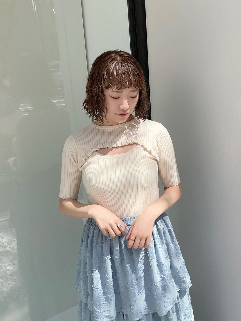 ブルー系のスカート、ホワイト系のニット/セーター、ホワイト系のパンプスを着用したレディースの春コーディネートの3枚目の写真