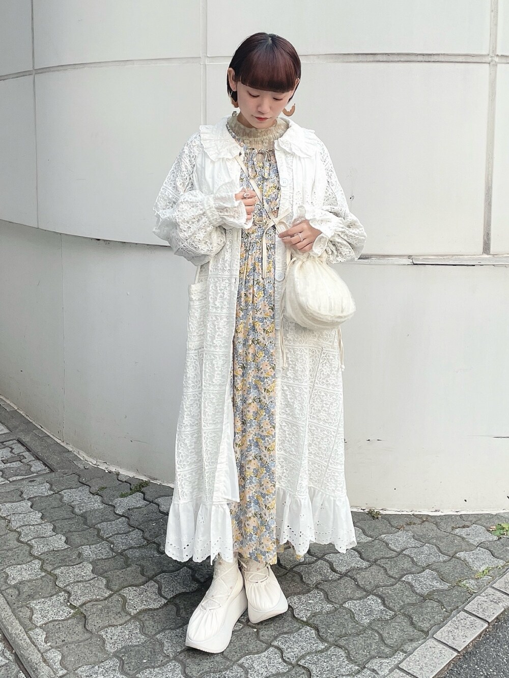 ホワイト系のトレンチコート、グリーン系のTシャツ/カットソー、イエロー系のワンピースを着用したレディースの冬コーディネートの2枚目の写真