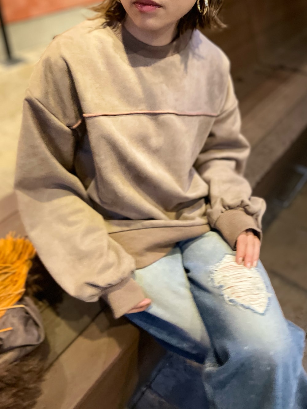 ベージュ系のスウェット、ブラウン系のベスト、ブラック系のブーツを着用したレディースの秋コーディネートの2枚目の写真