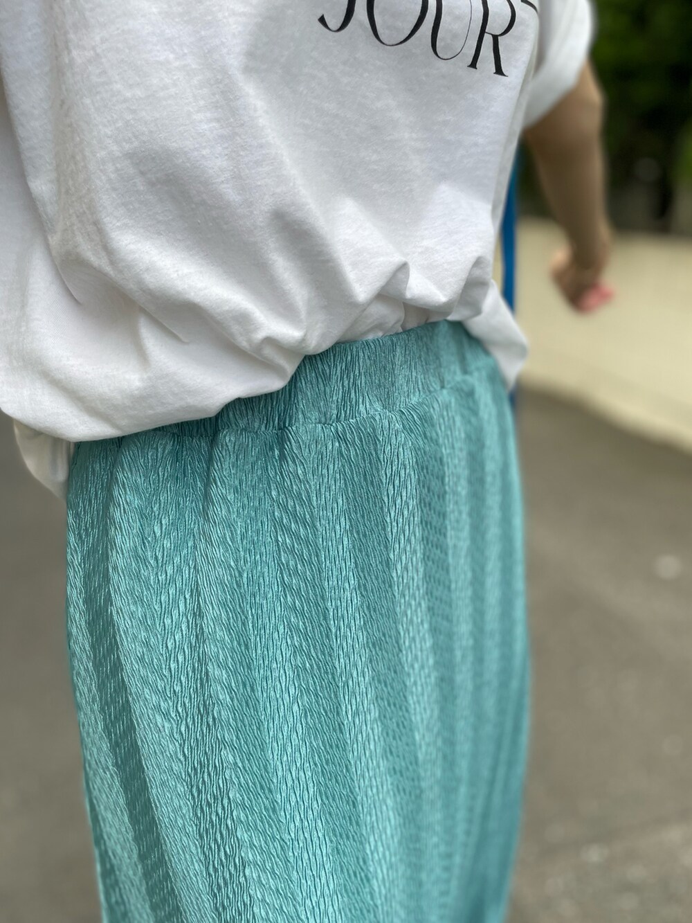 ブルー系のスカート、ホワイト系のTシャツ/カットソー、ブルー系のスニーカーを着用したレディースの夏コーディネートの3枚目の写真