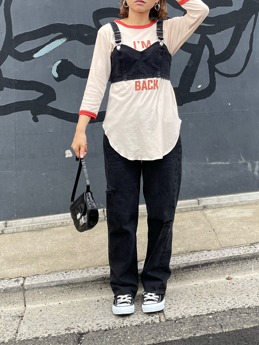 オレンジ系のTシャツ/カットソー、ブラック系のデニムパンツ、ブラック系のスニーカーを着用したレディースの春コーディネートの3枚目の写真