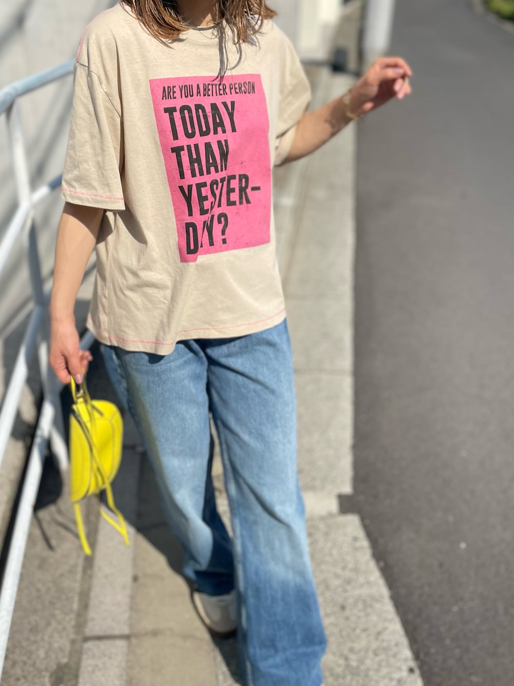 ベージュ系のTシャツ/カットソー、ブルー系のデニムパンツ、ホワイト系のスニーカーを着用したレディースの春コーディネートの4枚目の写真