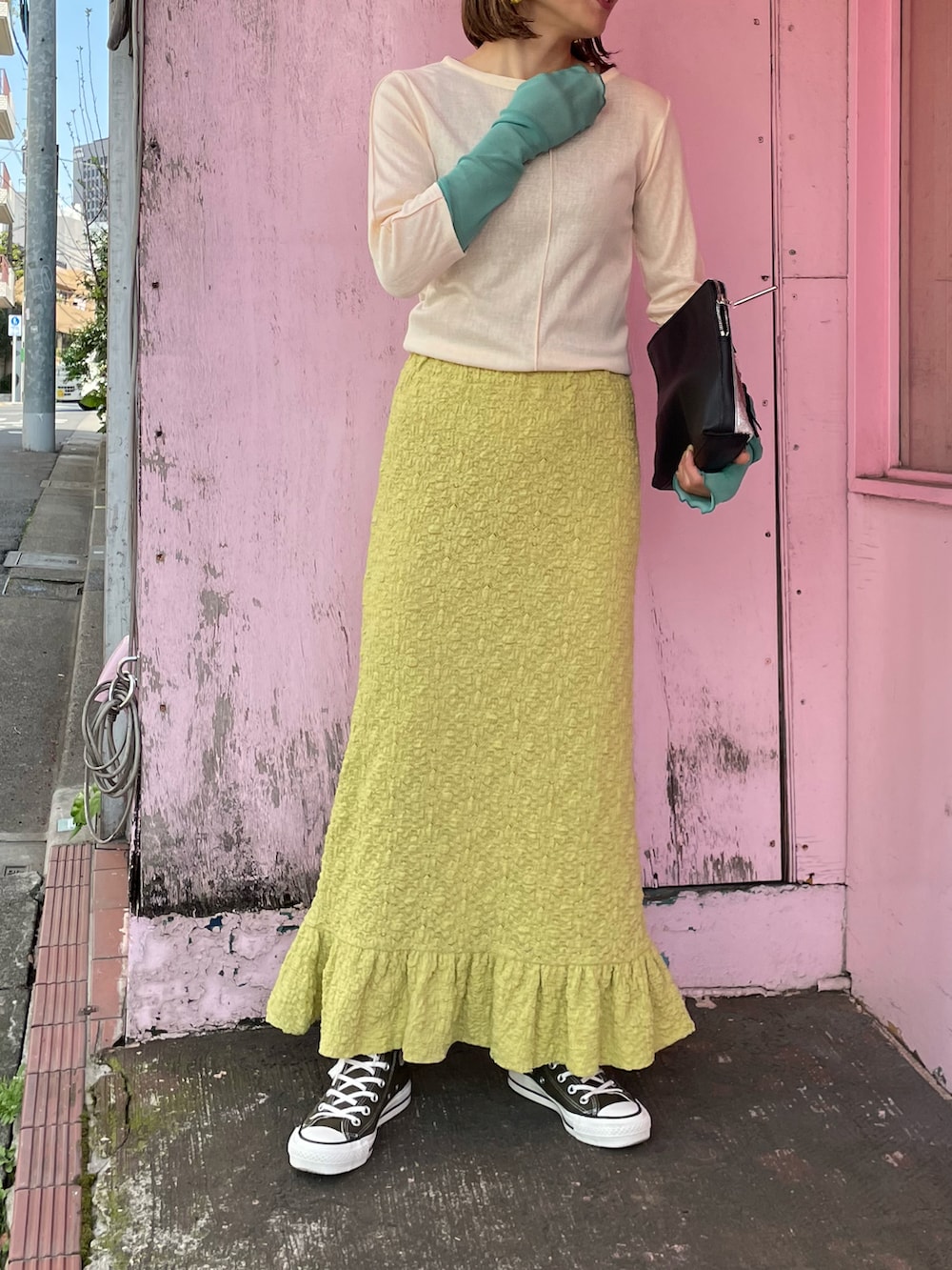 イエロー系のスカート、ベージュ系のTシャツ/カットソー、グリーン系のスニーカーを着用したレディースの春コーディネートの2枚目の写真