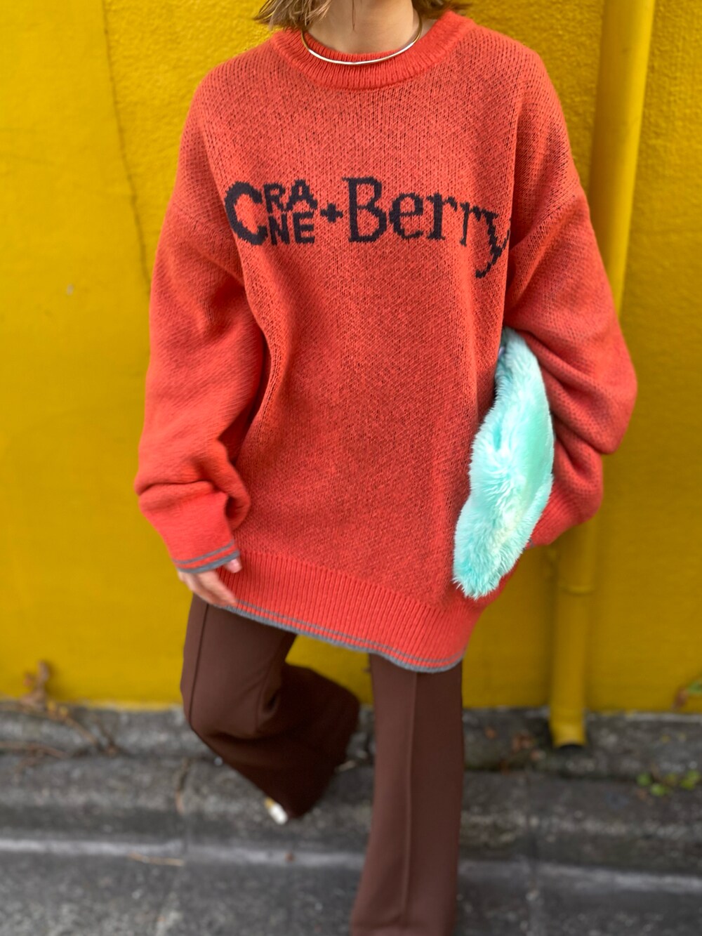 オレンジ系のニット/セーター、ブラウン系のその他パンツを着用したレディースの冬コーディネートの4枚目の写真