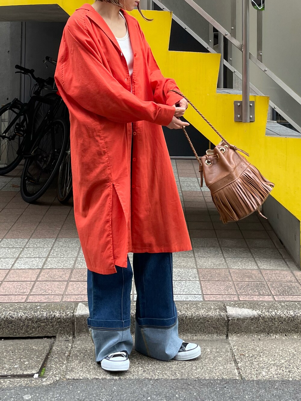 オレンジ系のシャツ/ブラウス、ホワイト系のタンクトップ、ブラック系のスニーカーを着用したレディースの春コーディネートの3枚目の写真