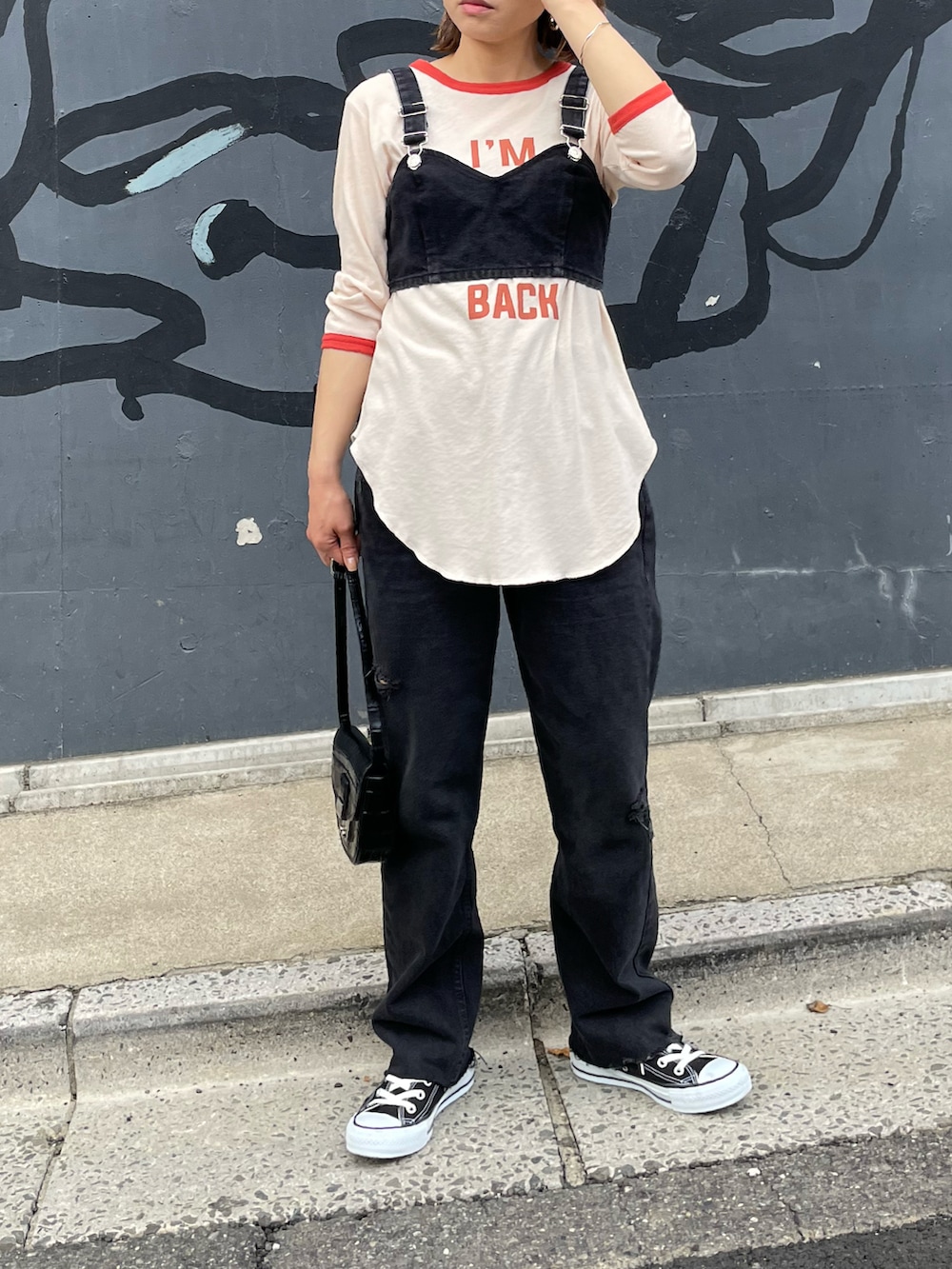 オレンジ系のTシャツ/カットソー、ブラック系のデニムパンツ、ブラック系のスニーカーを着用したレディースの春コーディネートの2枚目の写真