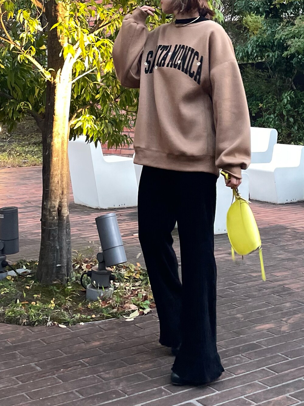 イエロー系のスウェット、ブラック系のその他パンツを着用したレディースの秋コーディネートの5枚目の写真