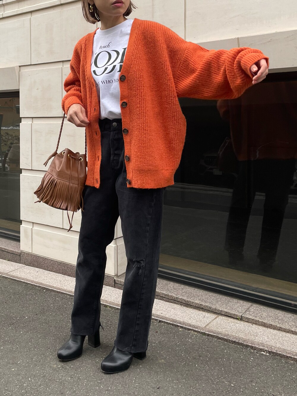 オレンジ系のカーディガン/ボレロ、ホワイト系のTシャツ/カットソーを着用したレディースの冬コーディネートの3枚目の写真