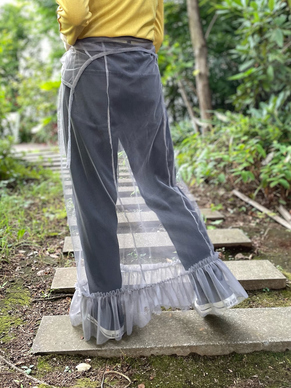 イエロー系のTシャツ/カットソー、グレー系のワンピース、ブラック系のデニムパンツを着用したレディースの秋コーディネートの5枚目の写真