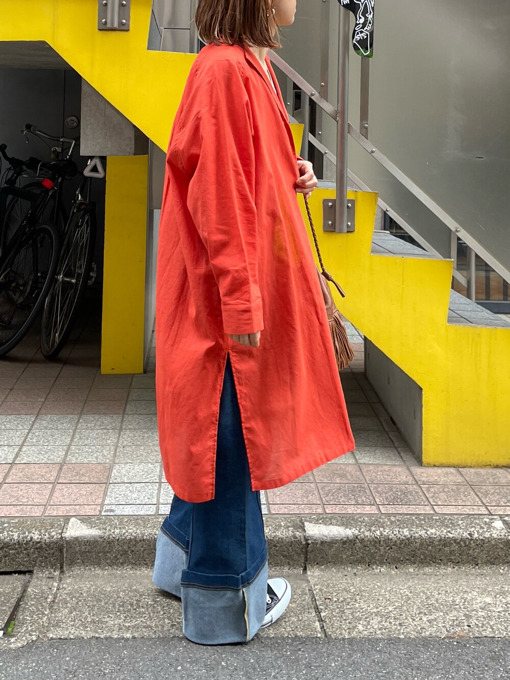 オレンジ系のシャツ/ブラウス、ホワイト系のタンクトップ、ブラック系のスニーカーを着用したレディースの春コーディネートの5枚目の写真