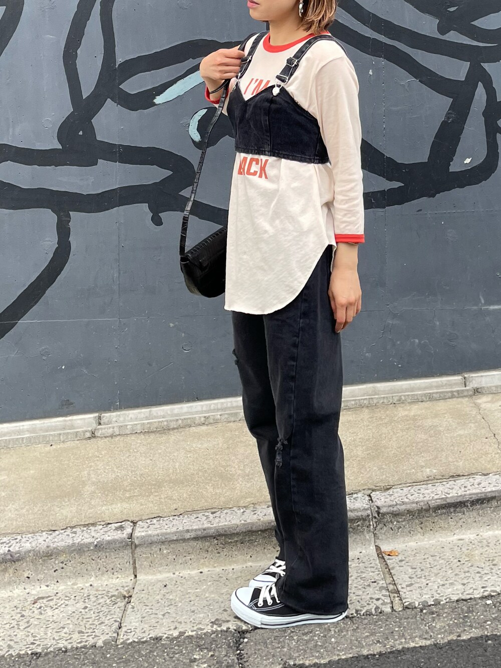 オレンジ系のTシャツ/カットソー、ブラック系のデニムパンツ、ブラック系のスニーカーを着用したレディースの春コーディネートの4枚目の写真