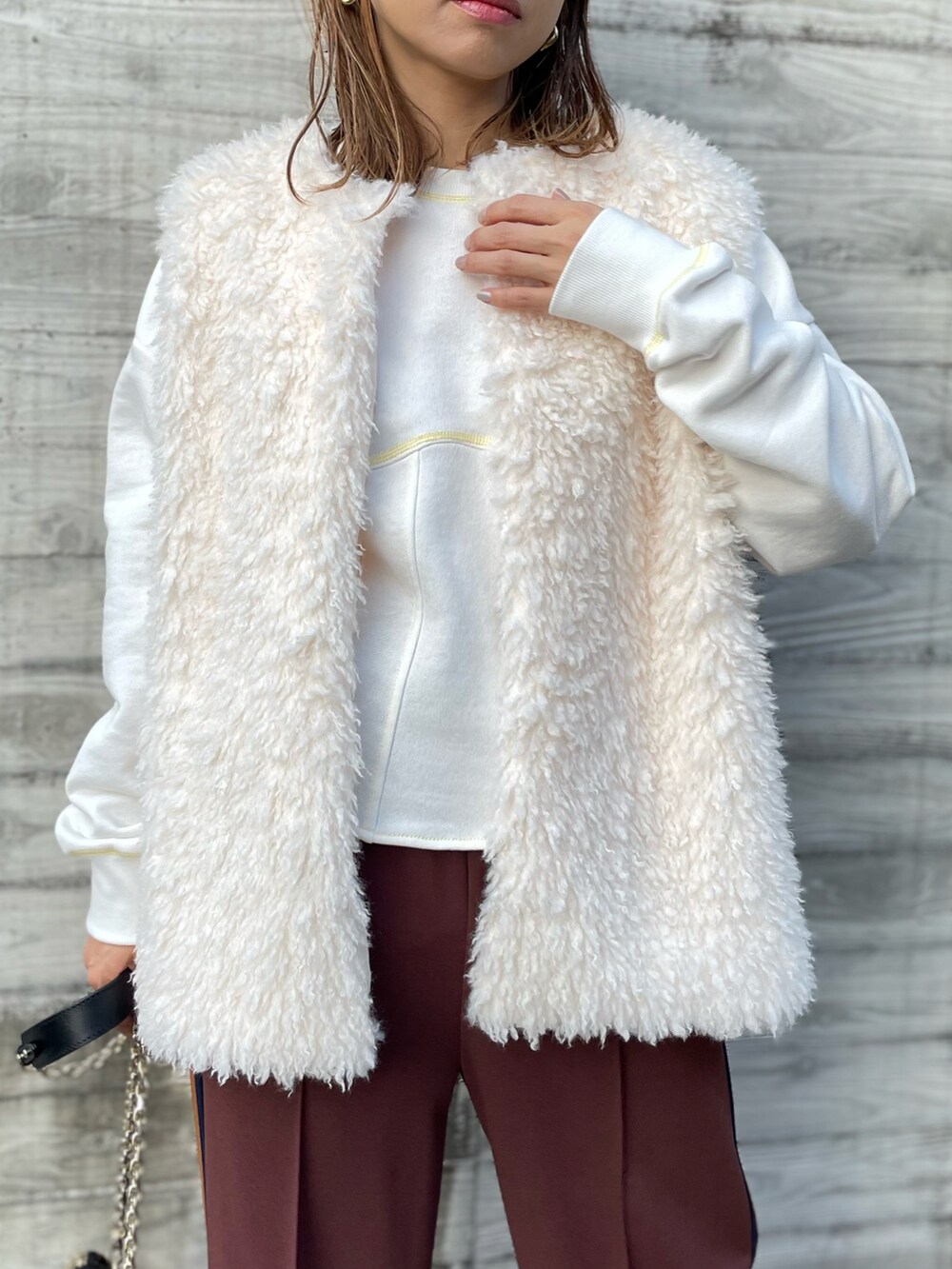 ホワイト系のベスト、ホワイト系のスウェット、ブラウン系のその他パンツを着用したレディースの秋コーディネートの2枚目の写真