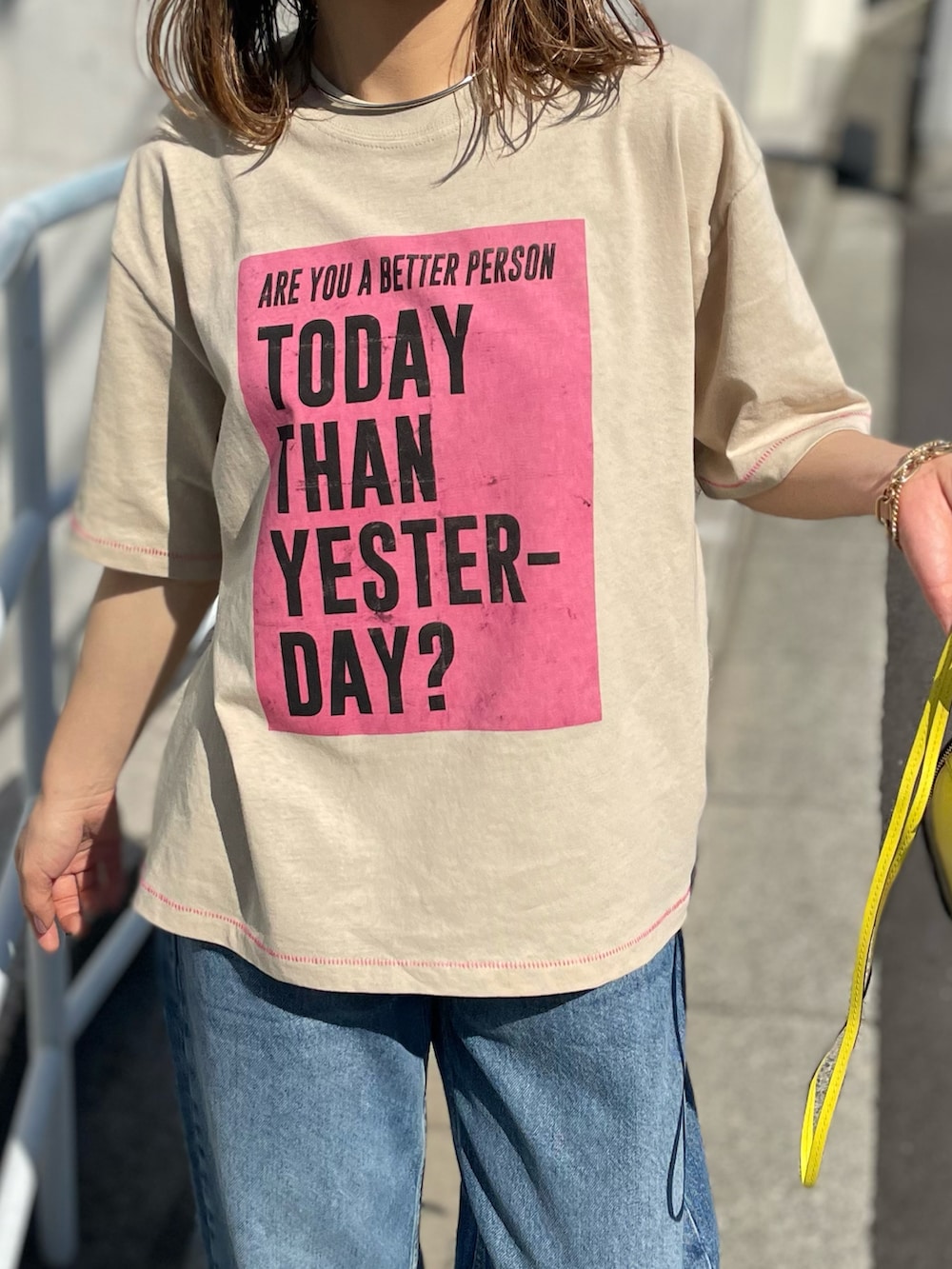 ベージュ系のTシャツ/カットソー、ブルー系のデニムパンツ、ホワイト系のスニーカーを着用したレディースの春コーディネートの3枚目の写真