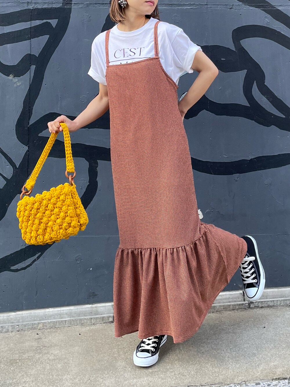 オレンジ系のワンピース、ホワイト系のTシャツ/カットソー、ブラック系のスニーカーを着用したレディースの春コーディネートの3枚目の写真