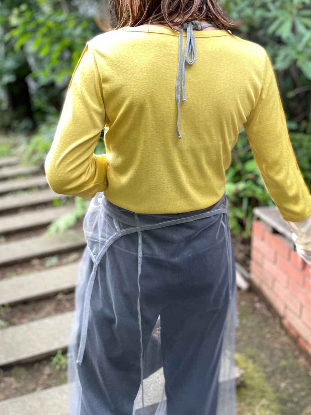 イエロー系のTシャツ/カットソー、グレー系のワンピース、ブラック系のデニムパンツを着用したレディースの秋コーディネートの3枚目の写真