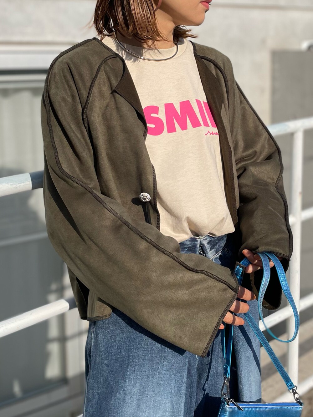 グリーン系のノーカラージャケット、ベージュ系のTシャツ/カットソーを着用したレディースの冬コーディネートの2枚目の写真