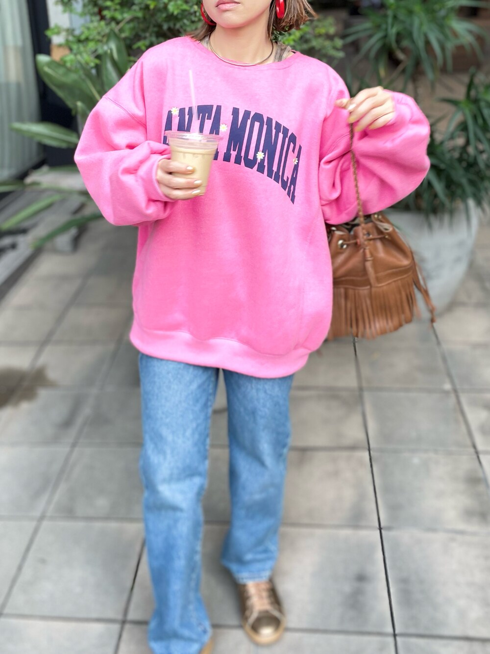 ピンク系のスウェット、ゴールド系のスニーカーを着用したレディースの冬コーディネートの2枚目の写真