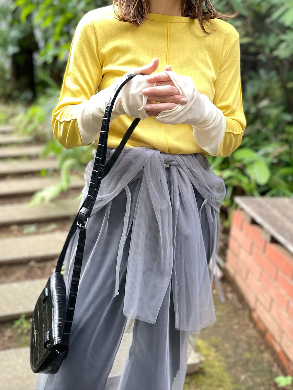 イエロー系のTシャツ/カットソー、グレー系のワンピース、ブラック系のデニムパンツを着用したレディースの秋コーディネートの2枚目の写真
