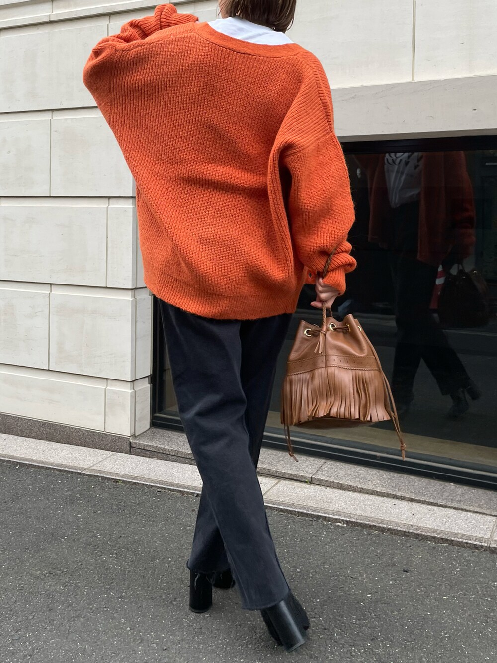 オレンジ系のカーディガン/ボレロ、ホワイト系のTシャツ/カットソーを着用したレディースの冬コーディネートの4枚目の写真