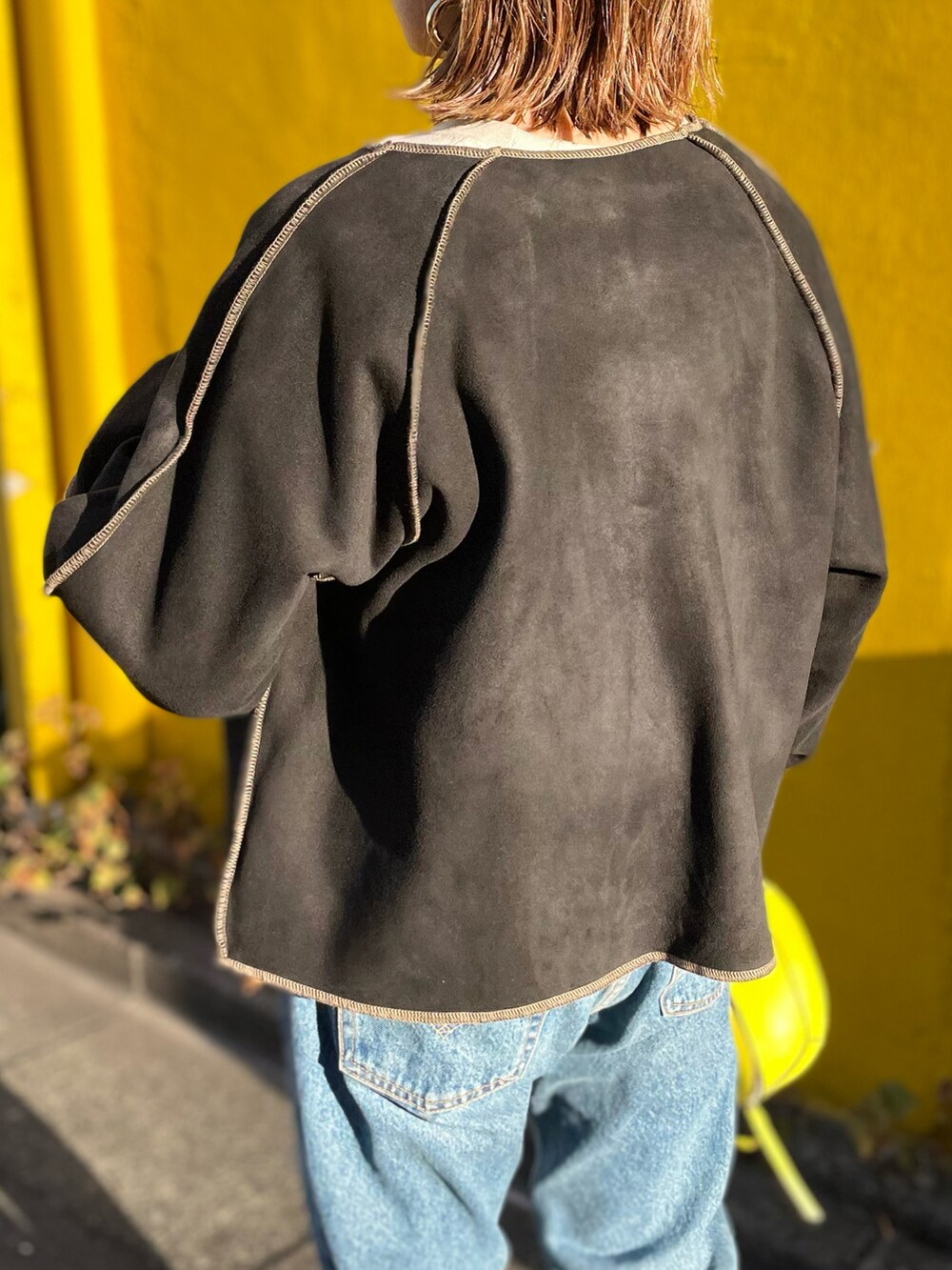 ブラック系のノーカラージャケット、ベージュ系のスウェット、ブラック系のブーツを着用したレディースの冬コーディネートの4枚目の写真