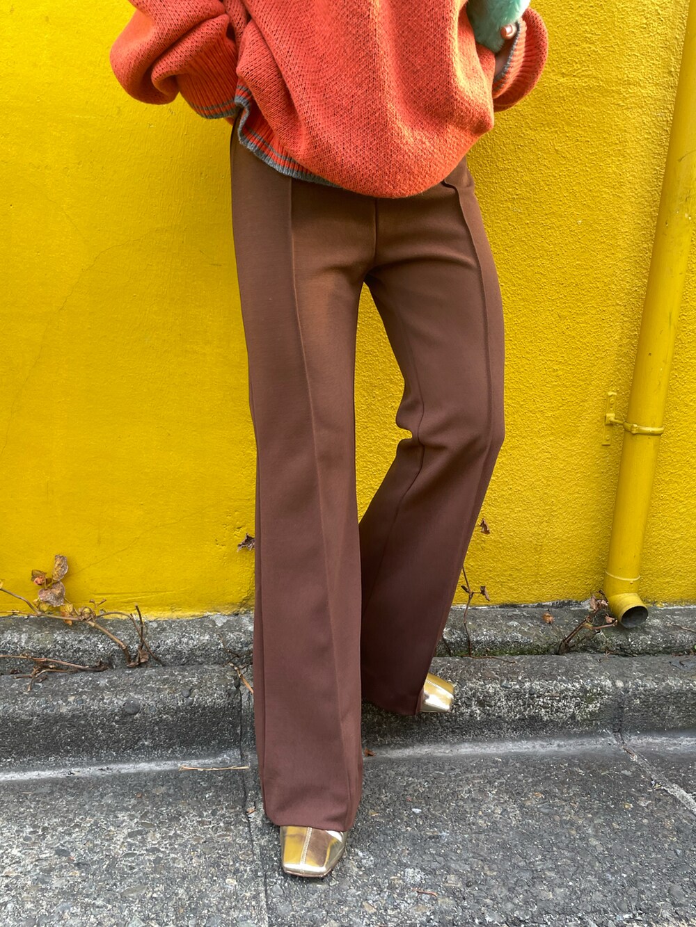 オレンジ系のニット/セーター、ブラウン系のその他パンツを着用したレディースの冬コーディネートの5枚目の写真