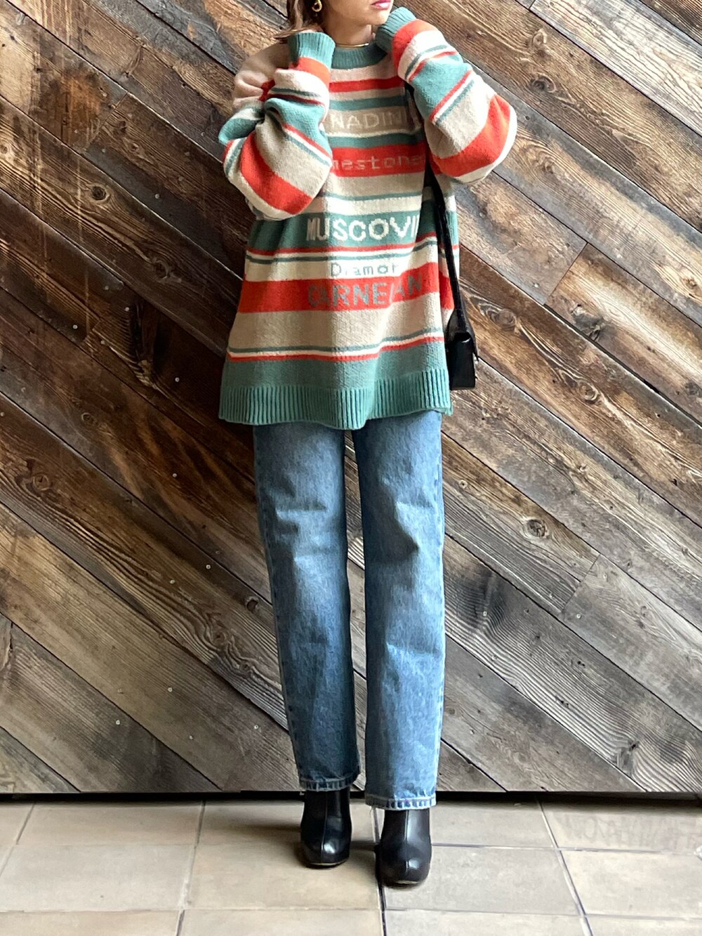 オレンジ系のニット/セーターを着用したレディースの冬コーディネートの5枚目の写真