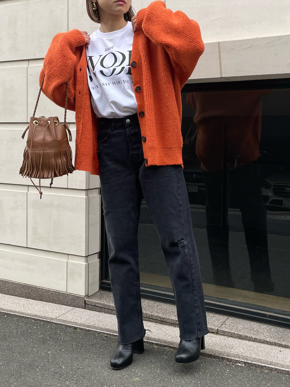 オレンジ系のカーディガン/ボレロ、ホワイト系のTシャツ/カットソーを着用したレディースの冬コーディネートの2枚目の写真