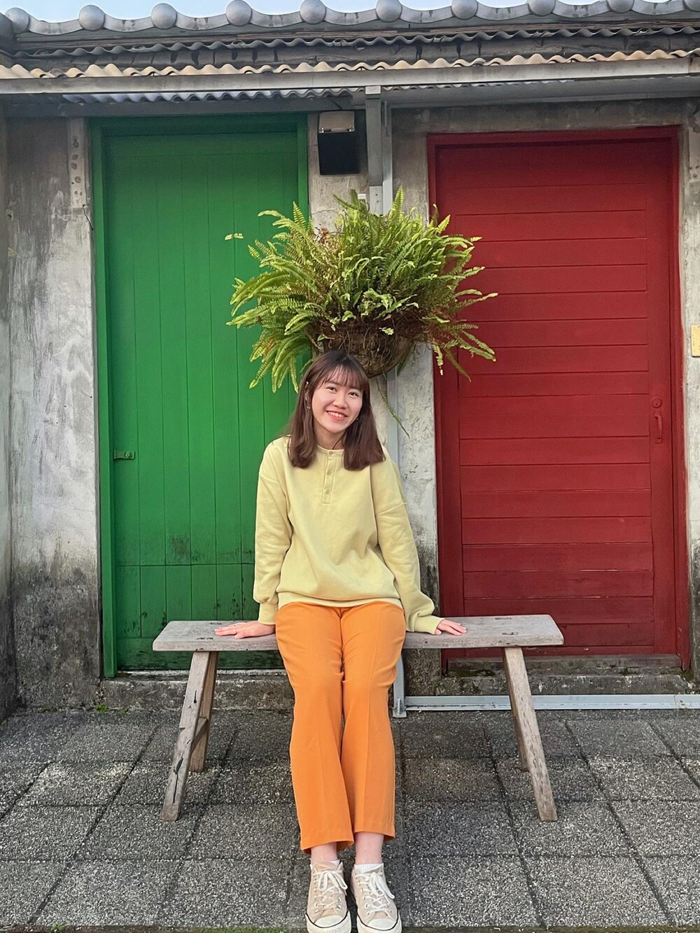 オレンジ系のスラックス、ベージュ系のシューズ、グリーン系のTシャツ/カットソーを着用したレディースの冬コーディネートの3枚目の写真