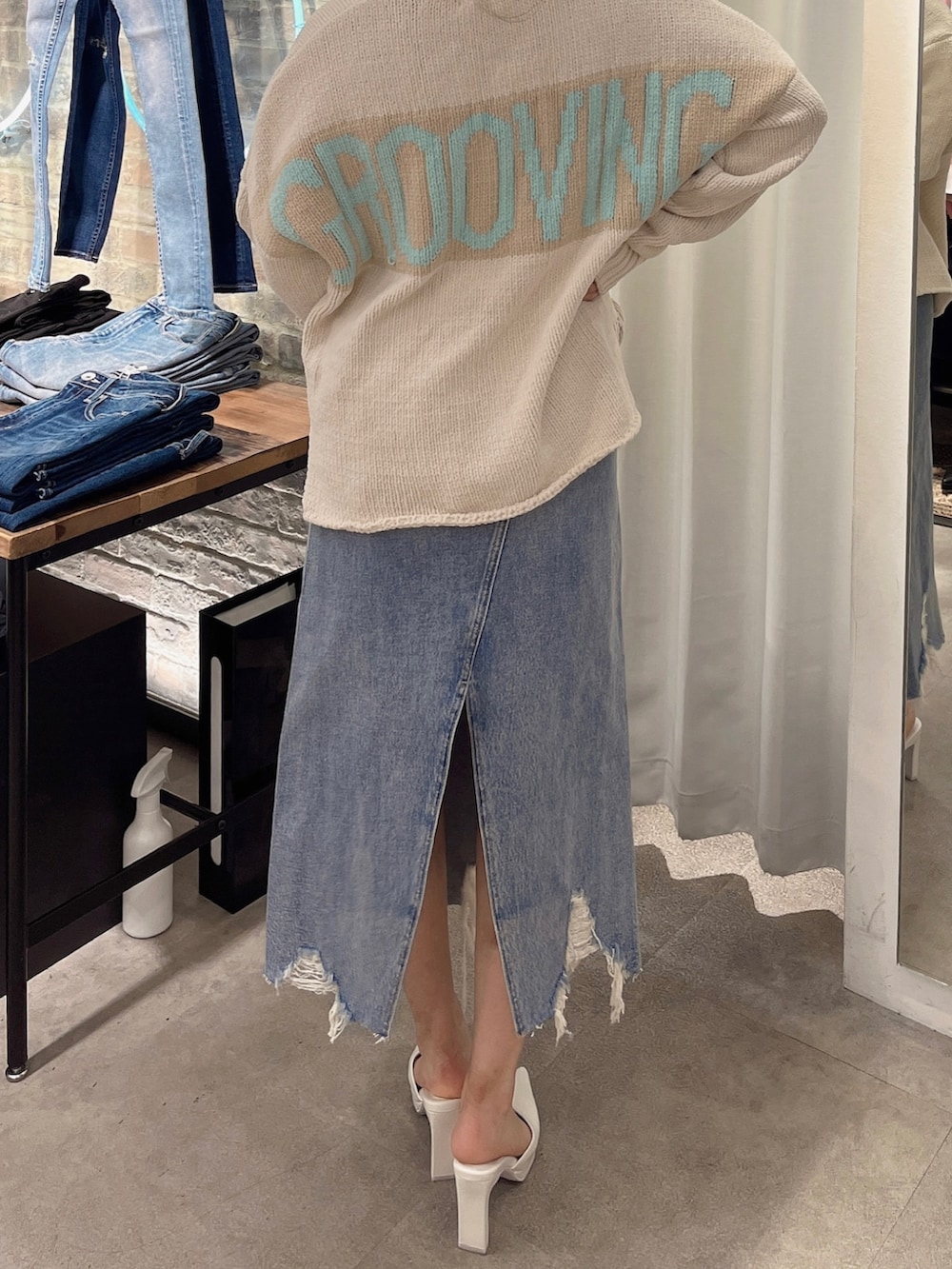 ホワイト系のニット/セーター、ブルー系のデニムスカート、ホワイト系のハンドバッグを着用したレディースの冬コーディネートの2枚目の写真