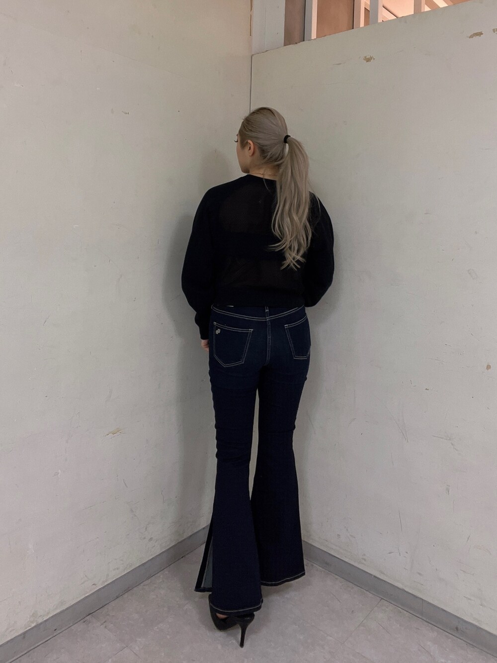 ブラック系のスウェット、ブルー系のデニムパンツ、ブラック系のパンプスを着用したレディースの冬コーディネートの3枚目の写真