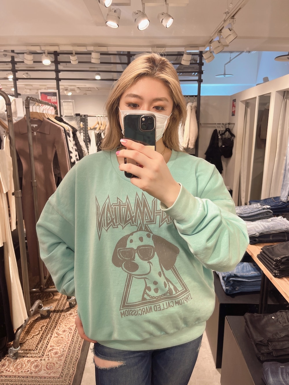 ブルー系のデニムパンツ、ブラック系のブーツ、グリーン系のスウェットを着用したレディースの冬コーディネートの2枚目の写真