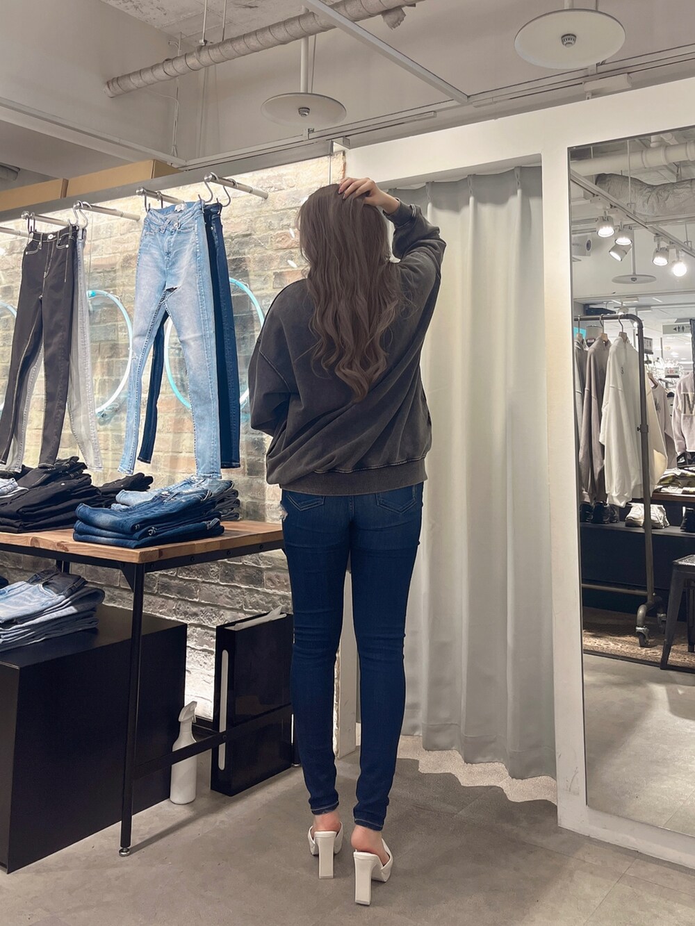 グレー系のスウェット、ブルー系のデニムパンツ、ホワイト系のパンプスを着用したレディースの冬コーディネートの2枚目の写真