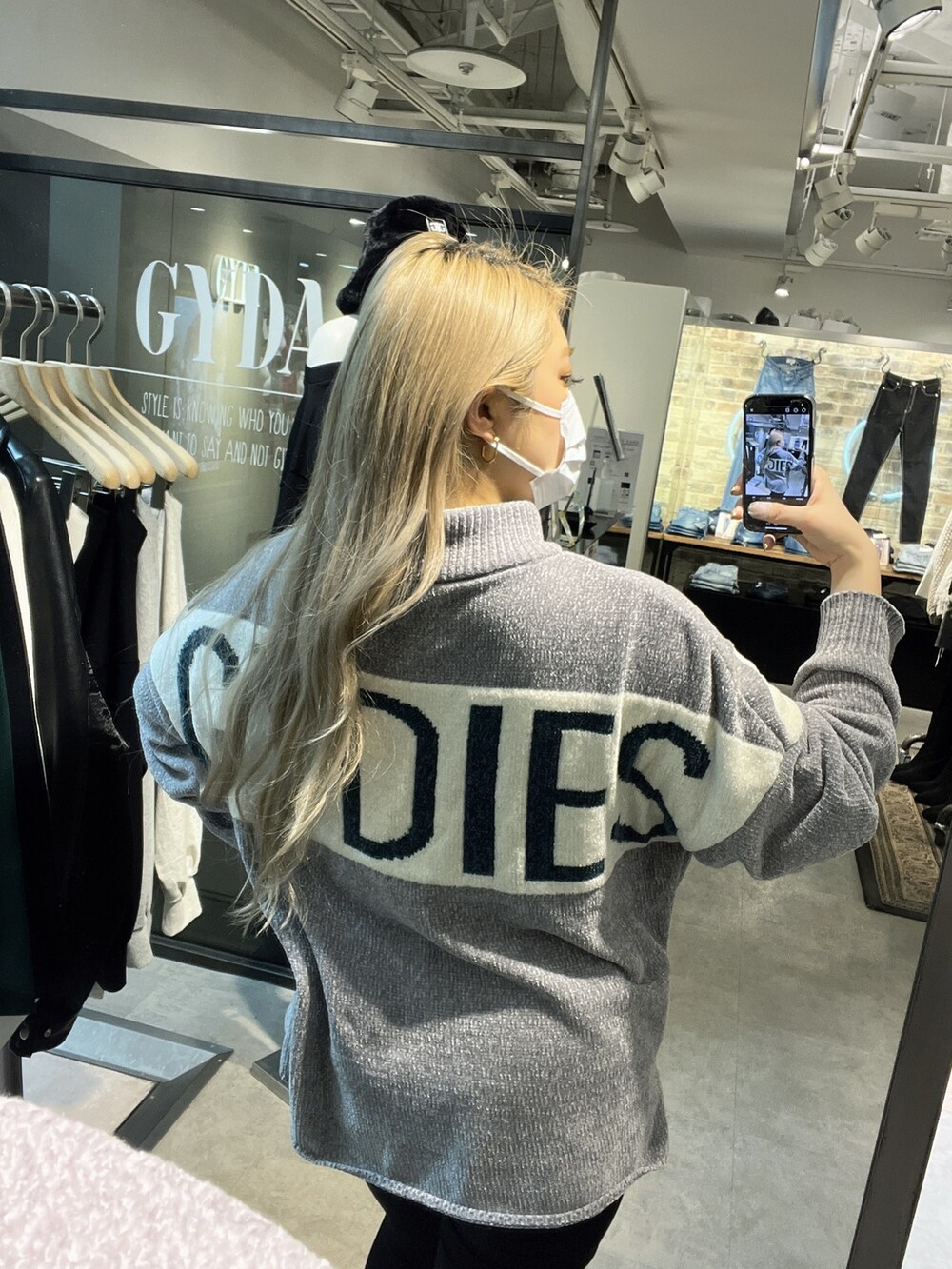 グレー系のニット/セーター、ブラック系のデニムパンツ、ホワイト系のパンプスを着用したレディースの秋コーディネートの3枚目の写真