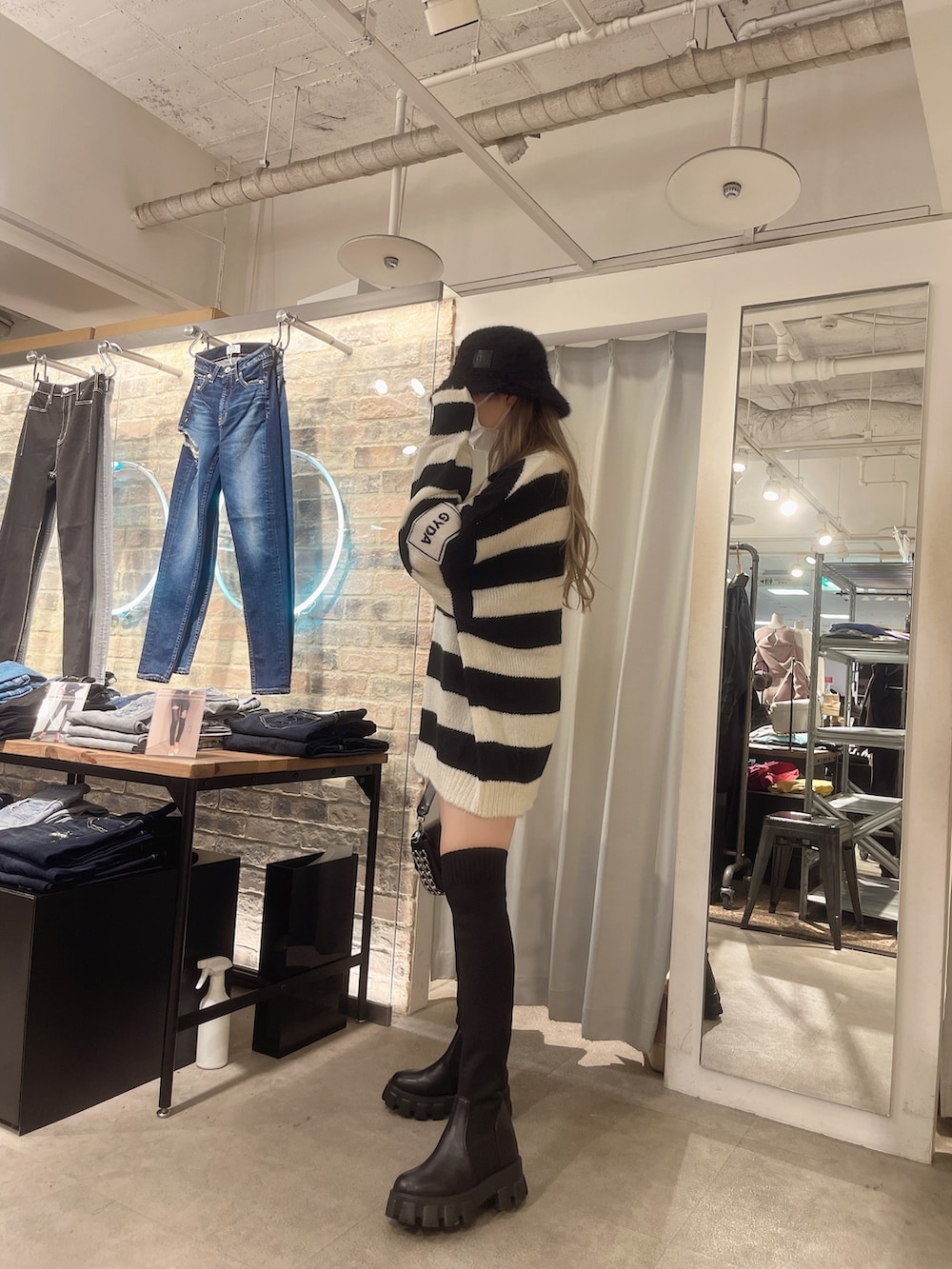 ブルー系のデニムパンツ、ブラック系のニット/セーター、ブラック系のハンドバッグを着用したレディースの秋コーディネートの2枚目の写真