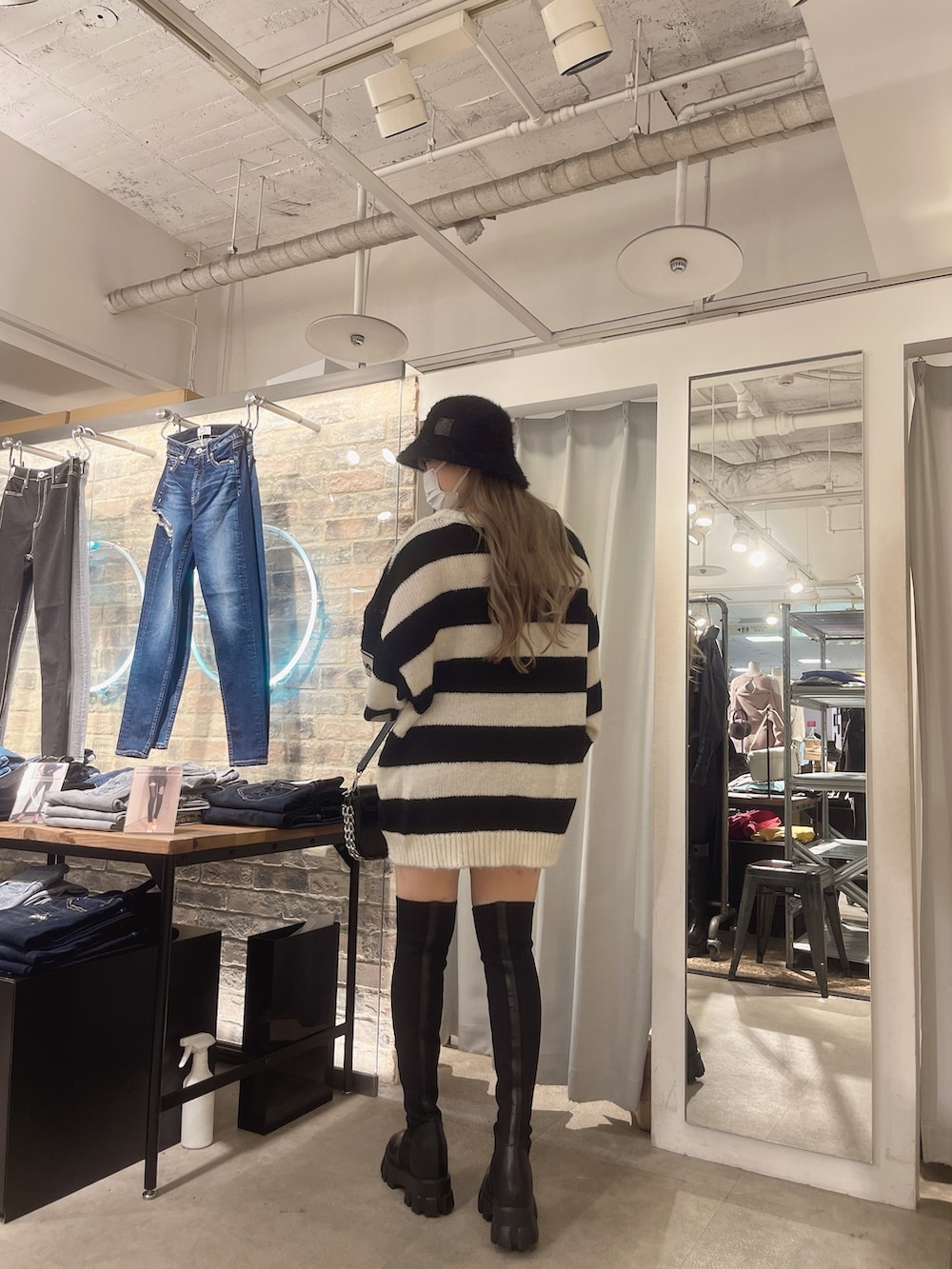 ブルー系のデニムパンツ、ブラック系のニット/セーター、ブラック系のハンドバッグを着用したレディースの秋コーディネートの3枚目の写真