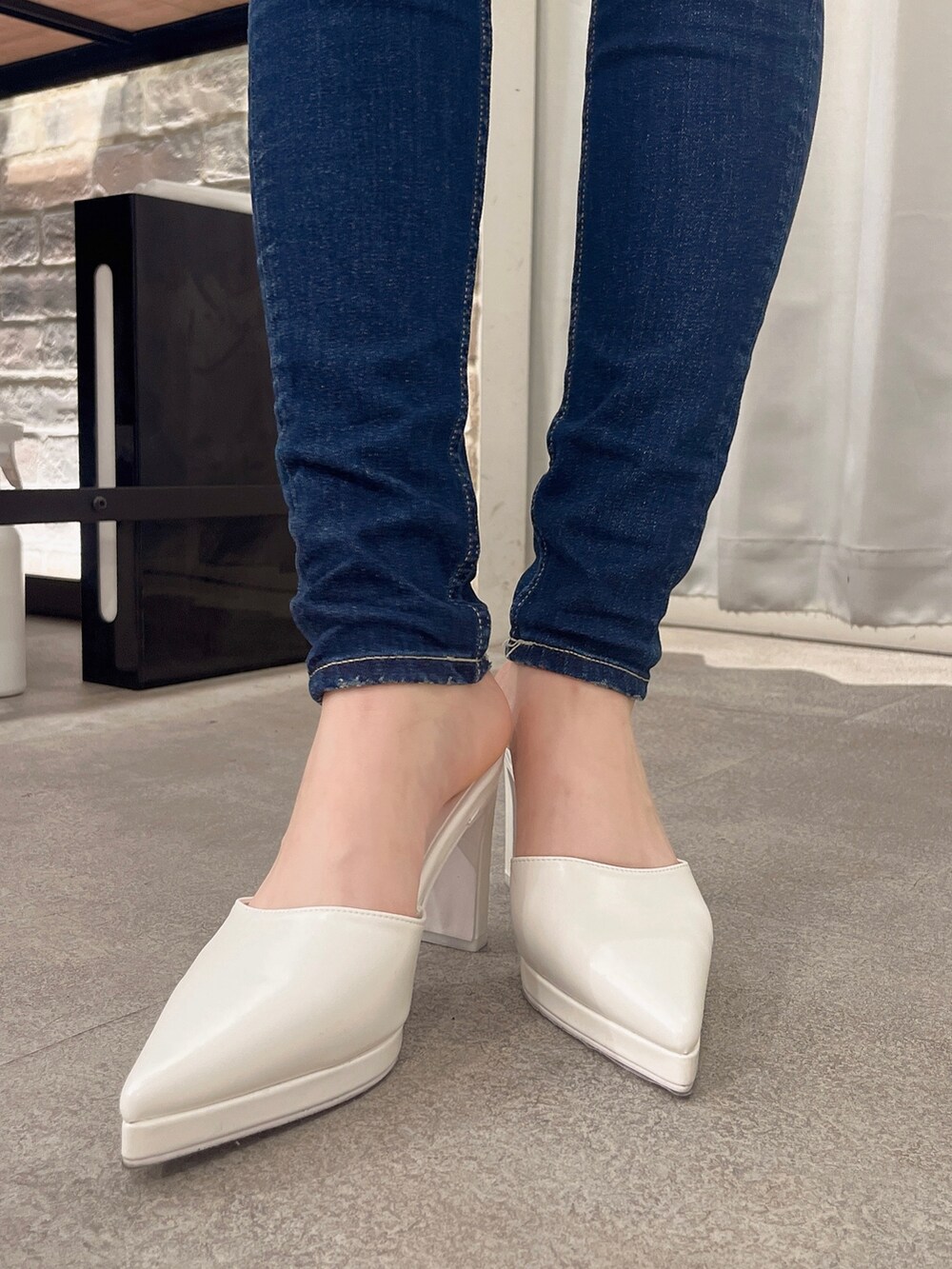 グレー系のスウェット、ブルー系のデニムパンツ、ホワイト系のパンプスを着用したレディースの冬コーディネートの4枚目の写真