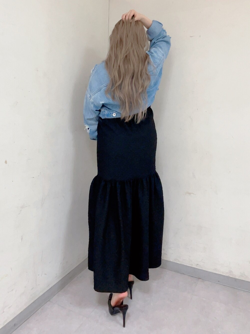 ブルー系のデニムジャケット、ブラック系のワンピース、ホワイト系のハンドバッグを着用したレディースの春コーディネートの2枚目の写真