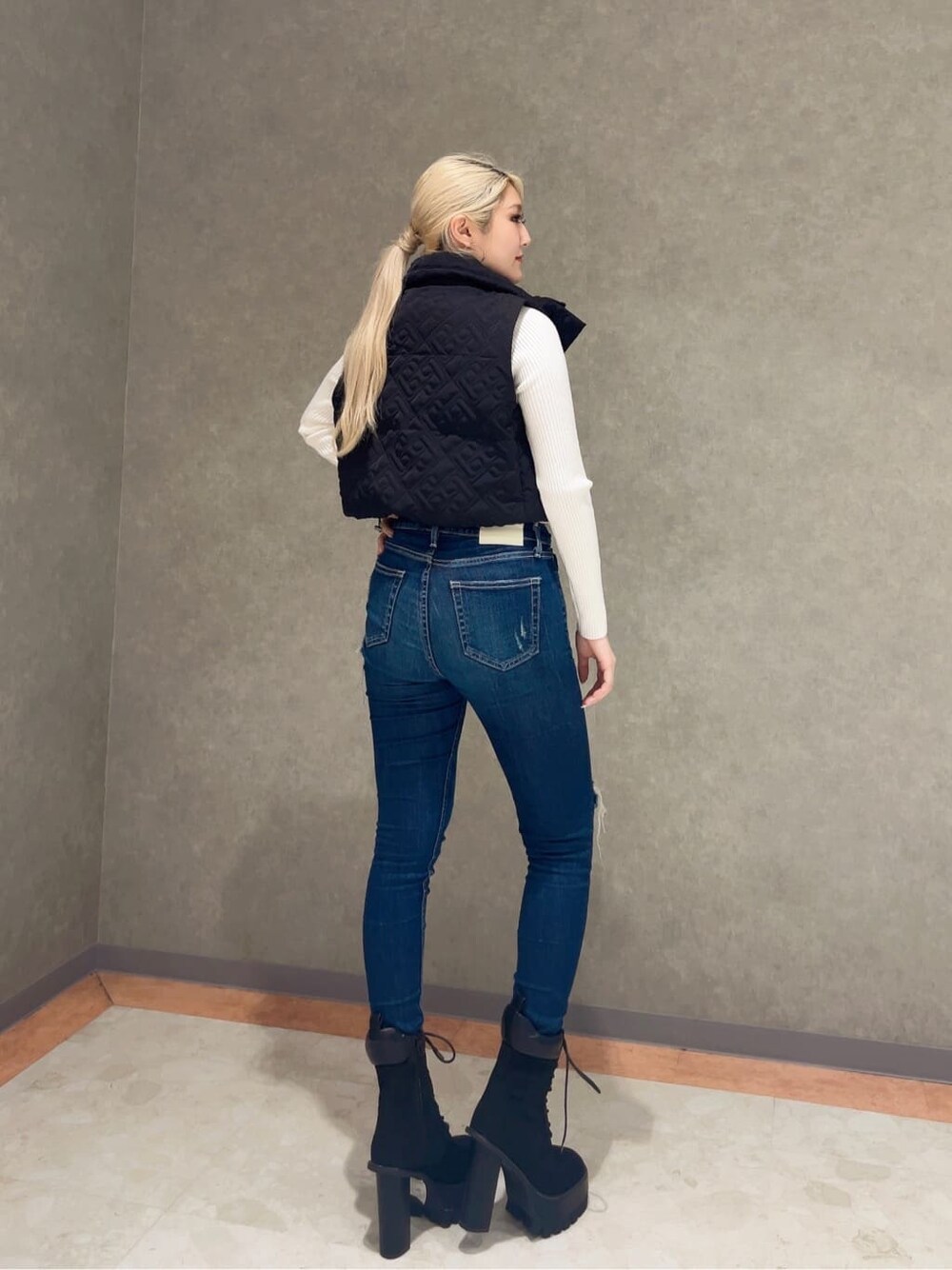 ブラック系のチューブトップ、ブルー系のデニムパンツ、ホワイト系のニット/セーターを着用したレディースの秋コーディネートの4枚目の写真