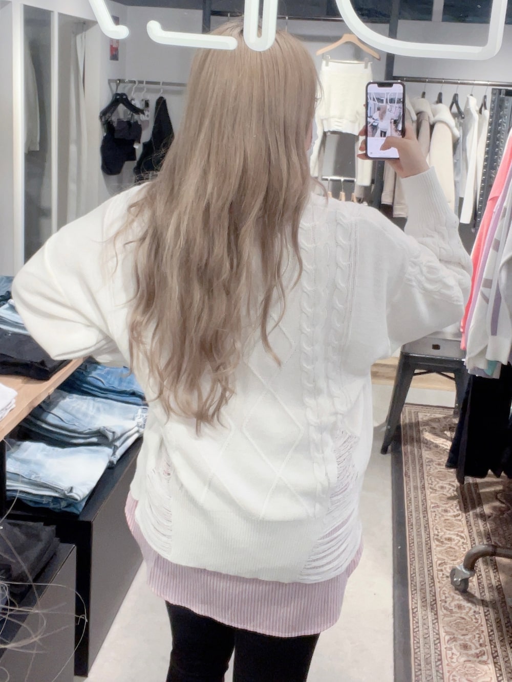 ホワイト系のニット/セーター、ピンク系のシャツ/ブラウス、ブラック系のデニムパンツを着用したレディースの冬コーディネートの2枚目の写真