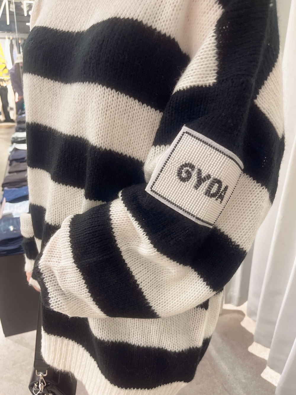 ブルー系のデニムパンツ、ブラック系のニット/セーター、ブラック系のハンドバッグを着用したレディースの秋コーディネートの4枚目の写真