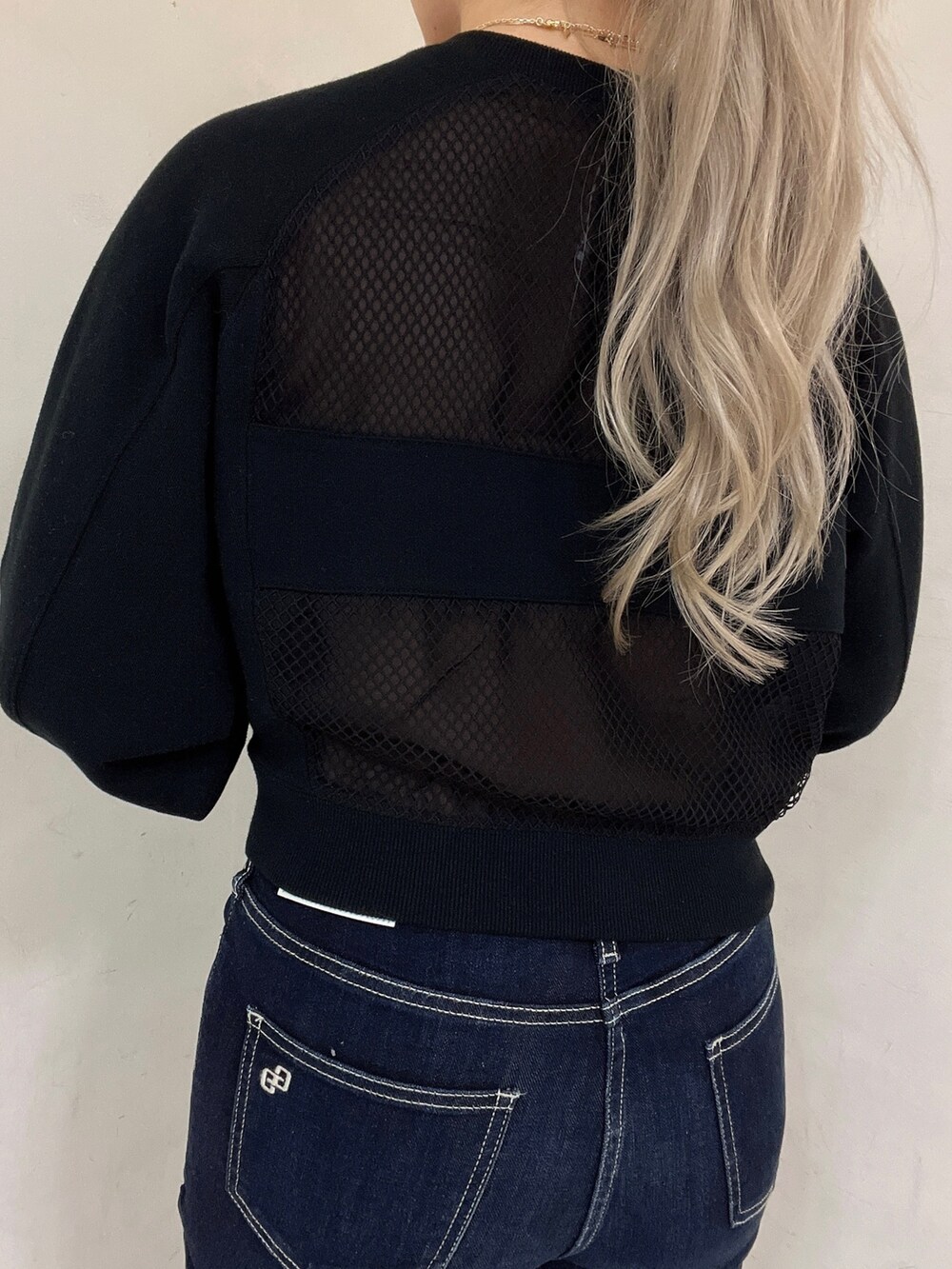 ブラック系のスウェット、ブルー系のデニムパンツ、ブラック系のパンプスを着用したレディースの冬コーディネートの4枚目の写真