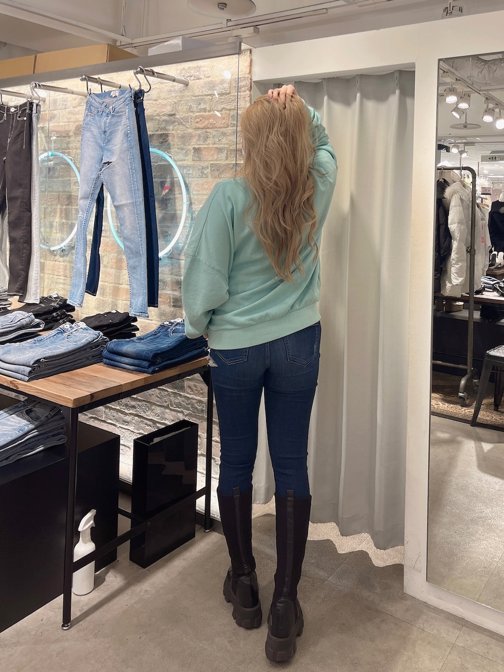 ブルー系のデニムパンツ、ブラック系のブーツ、グリーン系のスウェットを着用したレディースの冬コーディネートの3枚目の写真