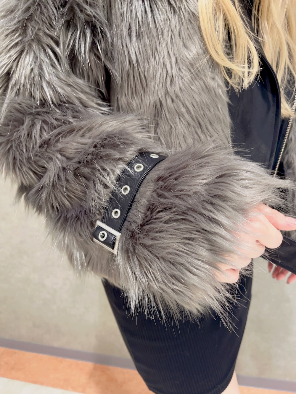 グレー系のライダースジャケット、ブラック系のハンドバッグ、ブラック系のブーツを着用したレディースの秋コーディネートの5枚目の写真