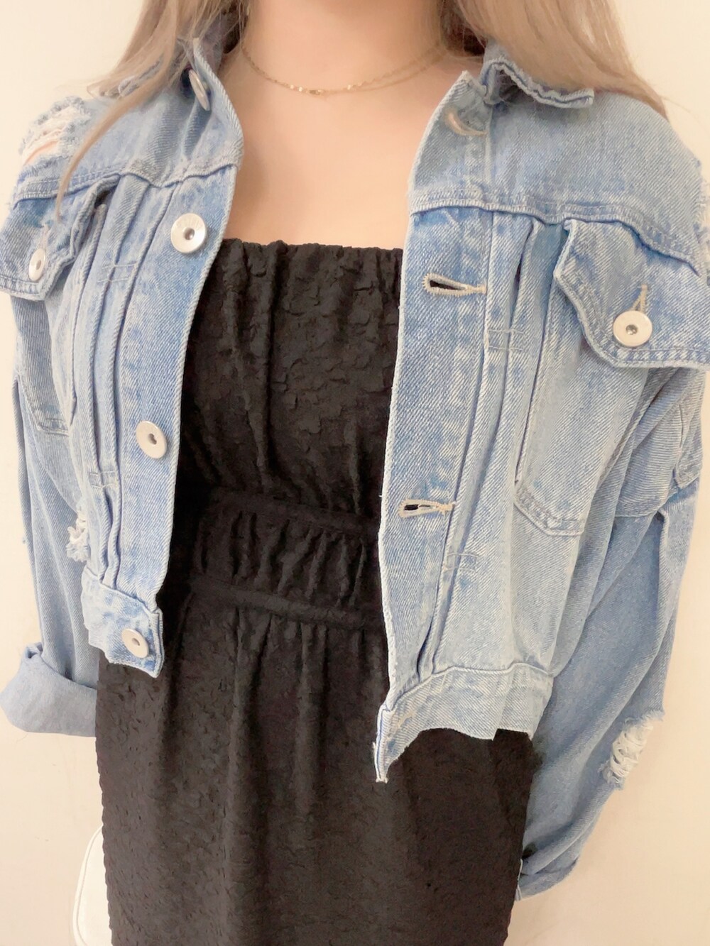 ブルー系のデニムジャケット、ブラック系のワンピース、ホワイト系のハンドバッグを着用したレディースの春コーディネートの4枚目の写真